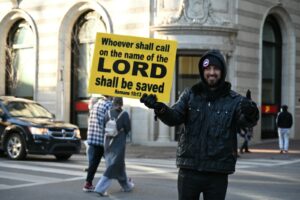 man in blue jacket holding blue and white signage