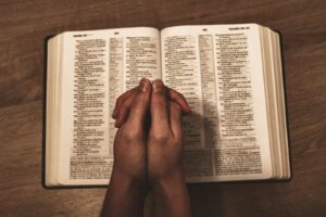 person holding book on brown wooden table